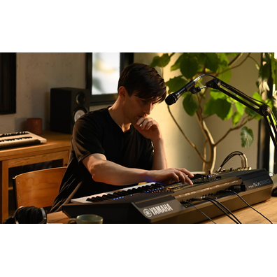 Photo of a person playing the Yamaha Arranger Workstation PSR-SX920 in a room with headphones on.