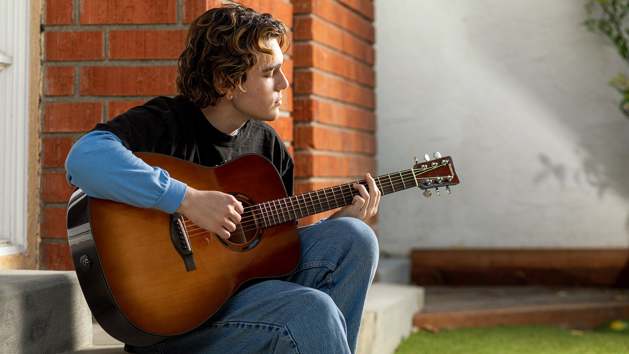 A man playing a TAG1 E acoustic guitar outdoors