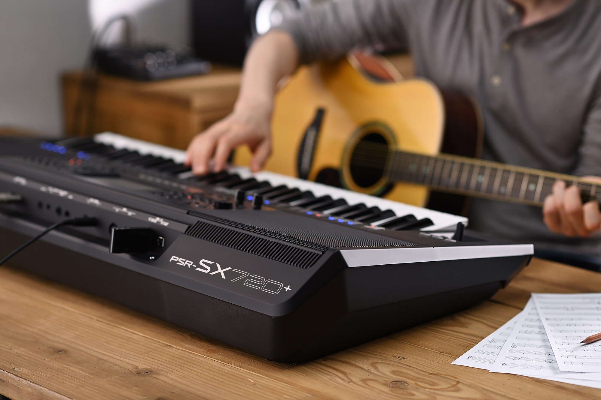 Photo of a person playing the Yamaha Arranger Workstation PSR-SX720+ while holding a guitar