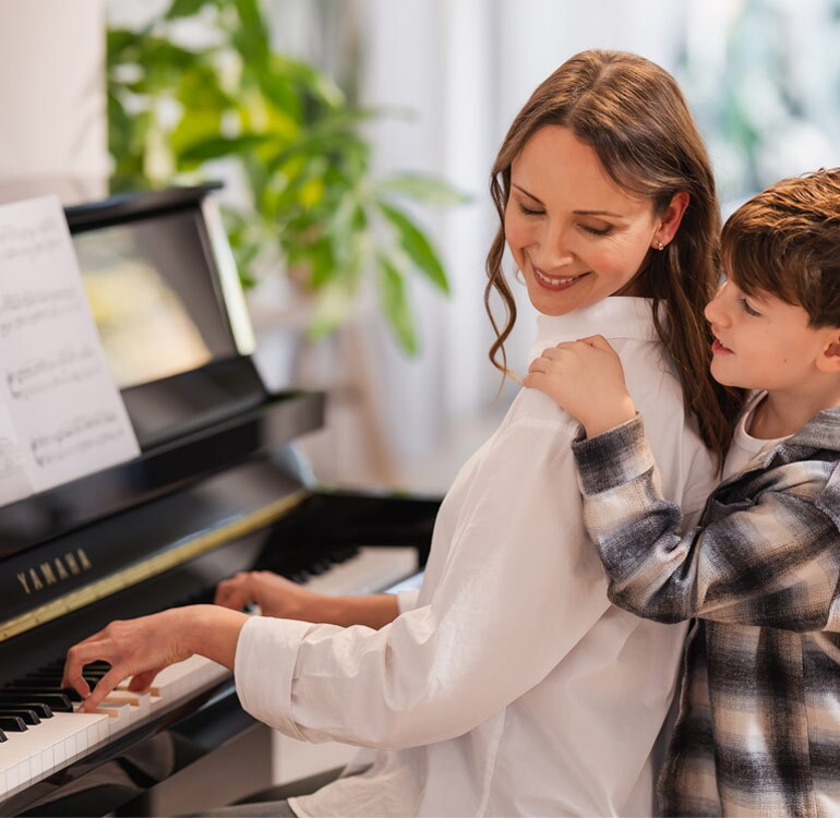 A mother and daughter enjoy playing the B Series upright piano