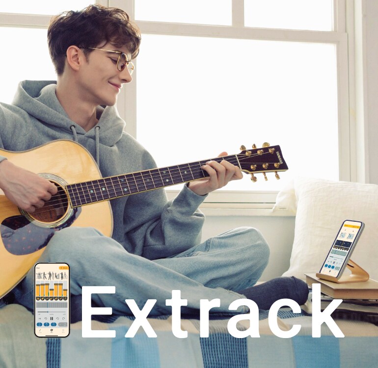 A man enjoys practising the guitar while sitting on the sofa and playing along with the Extrack music practice app